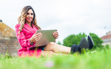 Young woman blogger influencer works on laptop on meadow in park