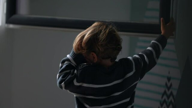 Little boy shutting window home. Child closes window