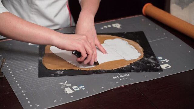The pastry chef cuts the shape of Santa Claus's boot from shortbread dough with a stencil. Step-by-step recipe for making Christmas cake