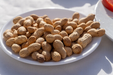 Roasted peanuts in the shell on a white plate.