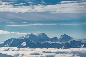 Obraz na płótnie Canvas Beautiful panorama of high rocky mountains with mighty glaciers and snowy peaks against the blue sky and clouds