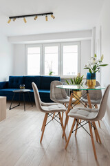 Elegant and modern interior of living room with window, stylish table and chairs and navy sofa. New apartment in hotel. Vertical.