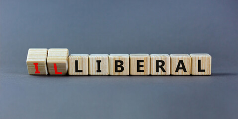 Illiberal or liberal symbol. Turned wooden cubes and changed the word illiberal to liberal. Beautiful grey background. Business, political and illiberal or liberal concept. Copy space.