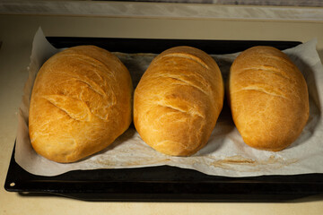 freshly baked loaves bread on a black baking sheet