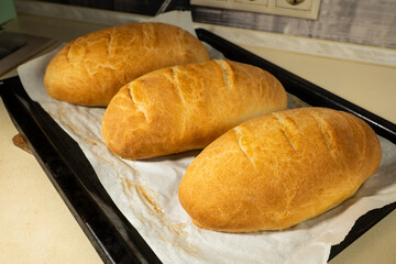 freshly baked loaves bread on a black baking sheet