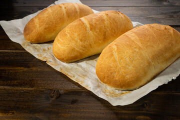 fresh baked loaves of bread on lie on a dark wooden table