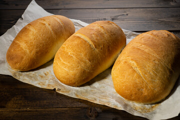 fresh baked loaves of bread on lie on a dark wooden table