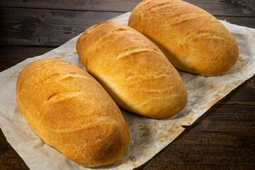 fresh baked loaves of bread on lie on a dark wooden table
