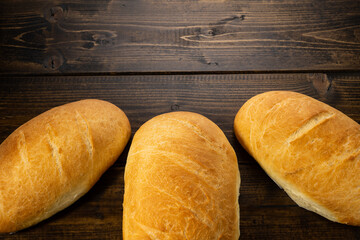 fresh baked loaves of bread on lie on a dark wooden table