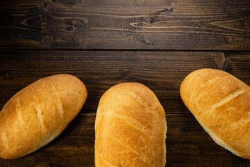 fresh baked loaves of bread on lie on a dark wooden table