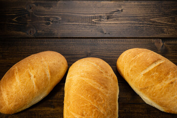fresh baked loaves of bread on lie on a dark wooden table