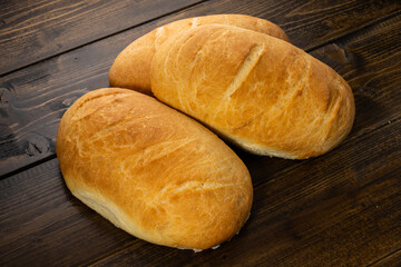 fresh baked loaves of bread on lie on a dark wooden table