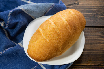 fresh baked loaves of bread on lie on a dark wooden table next to a blue towel rag
