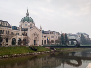 Fototapeta na wymiar The building of the Academy of Fine Arts and the Festina Lenta Bridge over the Miljacka River in Sarajevo