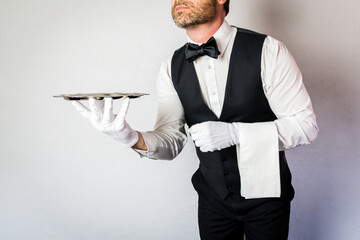 Portrait of Waiter or Butler in Vest and White Gloves Holding Silver Serving Tray on White...