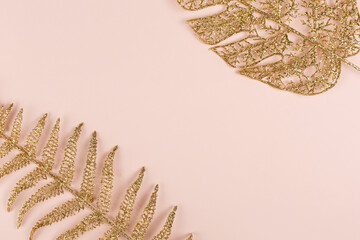Two golden leaves on the pink background. Perfect Christmas or New Year banner. Top view. Copy space.