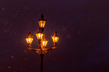 Street lamp on the background of falling snow. Night landscape, blurred background of snowflakes. Falling snow in the light of street lamps at night.
