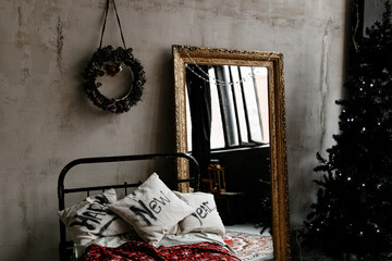 The bedroom is decorated for Christmas. Cozy dark vintage interior: plaid, antique bed, Christmas tree.