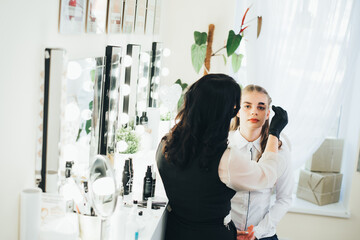 a girl in a beauty salon has an eyebrow lamination procedure, smears with white paste