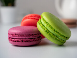 three macaroons on a white background. The back has a light blurred background. Side view. Delicious sweet dessert