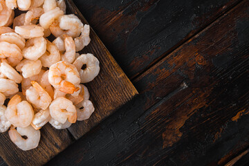  Boiled peeled prawns, on wooden serving board, on old dark  wooden table , top view flat lay, with copy space for text