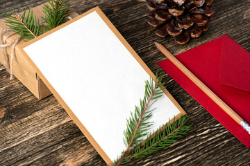 Christmas background with a blank sheet of paper with a red envelope and a pencil surrounded by Christmas decorations. Letter to Santa Claus or wish list