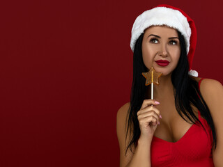 Girl in a christmas santa hat with a candy on a stick in her hand
