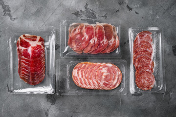 Vacuum packed sausage Prosciutto salami, on gray stone table background, top view flat lay, with...