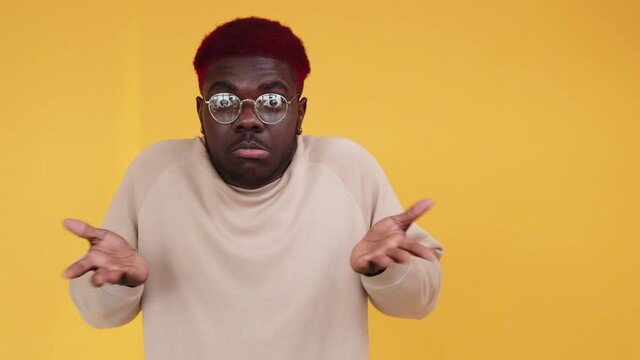 No idea. Clueless man. Doubt emotion. Boomerang motion. Uncertain African guy shrugging shoulders in dont know reaction isolated on free space orange background GIF loop.