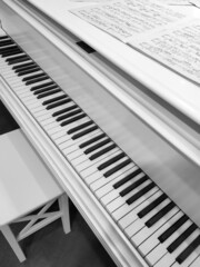 The piano is white, with black and white keys, with notes on the surface of the lid of the musical...