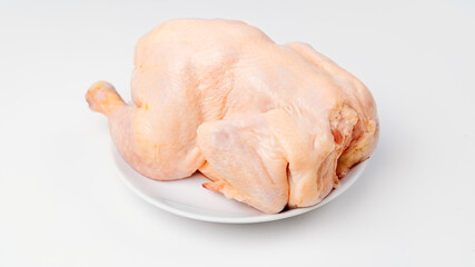carcass of raw chicken on a white plate on a white background. 