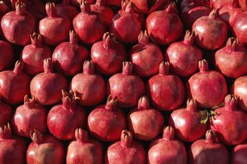Fresh juicy vitamin pomegranates are arranged in rows. Harvest of exotic Azerbaijani fruits, background and food texture.