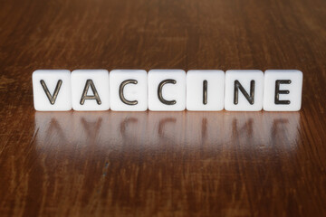 Vaccine word on blocks. 3D Vaccine message on wooden background with reflection