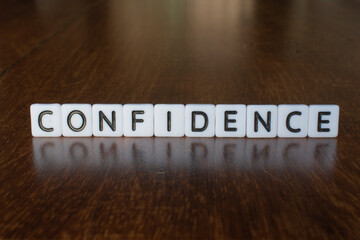 Confidence word on blocks. 3D Confidence message on wooden background with reflection