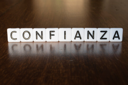 Confidence (Confianza) word on blocks. 3D Confidence (Confianza) message on wooden background with reflection