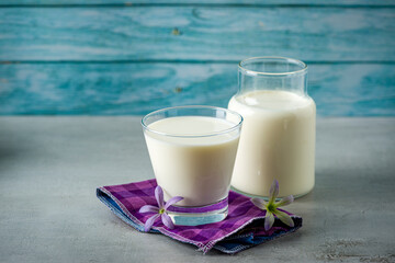 Milk. Glass of milk over purple checkered fabric on gray and blue background.