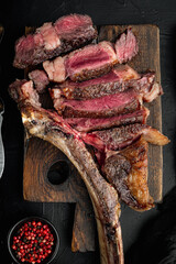Pieces of delicious barbecued meat medium rare beef steak,  tomahawk cut, on wooden serving board,...
