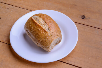 French rolls. Brazilian breads on a white plate on wooden table.
