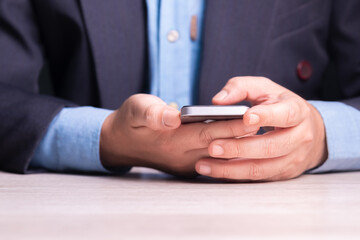 Closeup businessman holding smart phone in his hand on the table, going to text the message for work