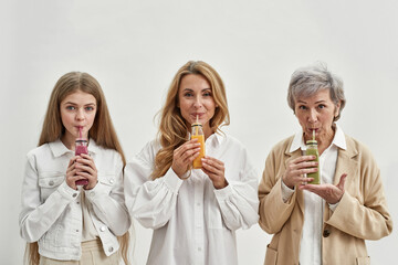 Happy three generations of women drink fruit juices