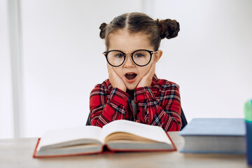 Little girl wearing glasses and doing homework. Upset.