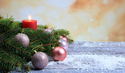 Christmas background with spruce branches, pink and violet balls, red candles, and ornaments