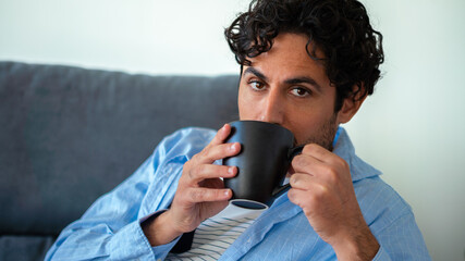 Caucasian man with beard drinking morning expresso coffee and looking at camera
