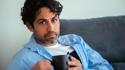 Caucasian man with beard drinking morning expresso coffee and looking at camera