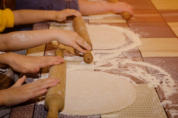 The hands of children knead the dough from which they will make bread, pasta, cake or pizza. 