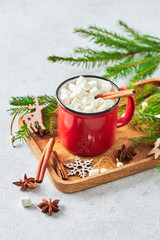Red cup of hot cocoa with marshmallows and candy canes on with christmas tree