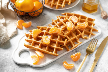 Homemade ginger waffles with tangerines. Delicious Christmas pastries on a light background closeup