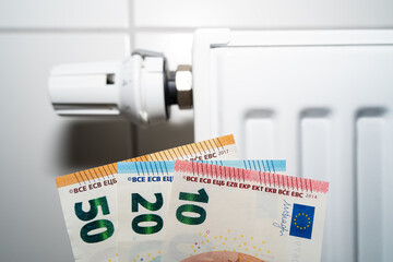 Euro money in front of a white radiator because gas is becoming more expensive 