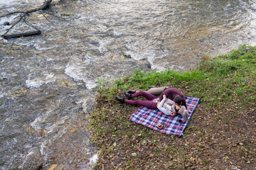 a guy and a girl are drinking tea near the river
