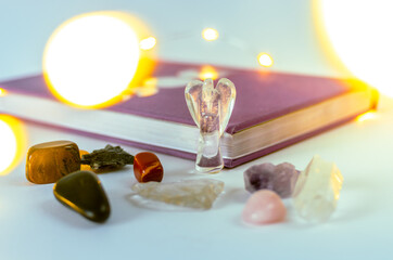 Close up angel crystal from clear quartz near a moon journal with Christmas lights and incense on background. Concept: spiritual self care practices
